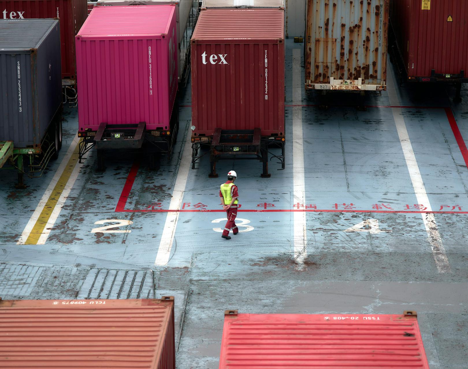 Person managing freight schedules with digital tools near cargo trucks